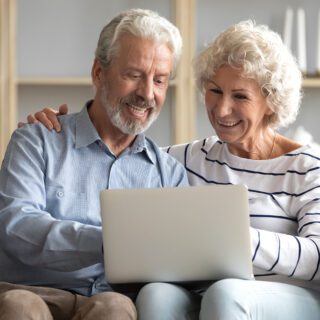 senior couple looking at long term care insurance on a laptop at home